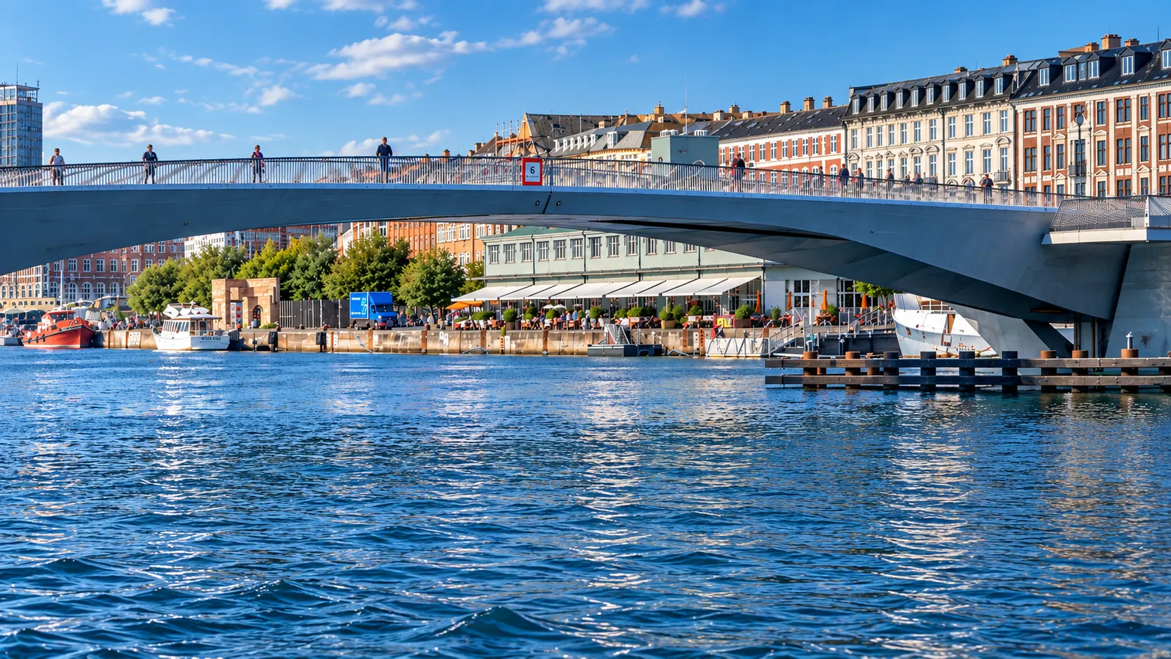 Private boat cruising past a Copenhagen bridge and waterfront architecture